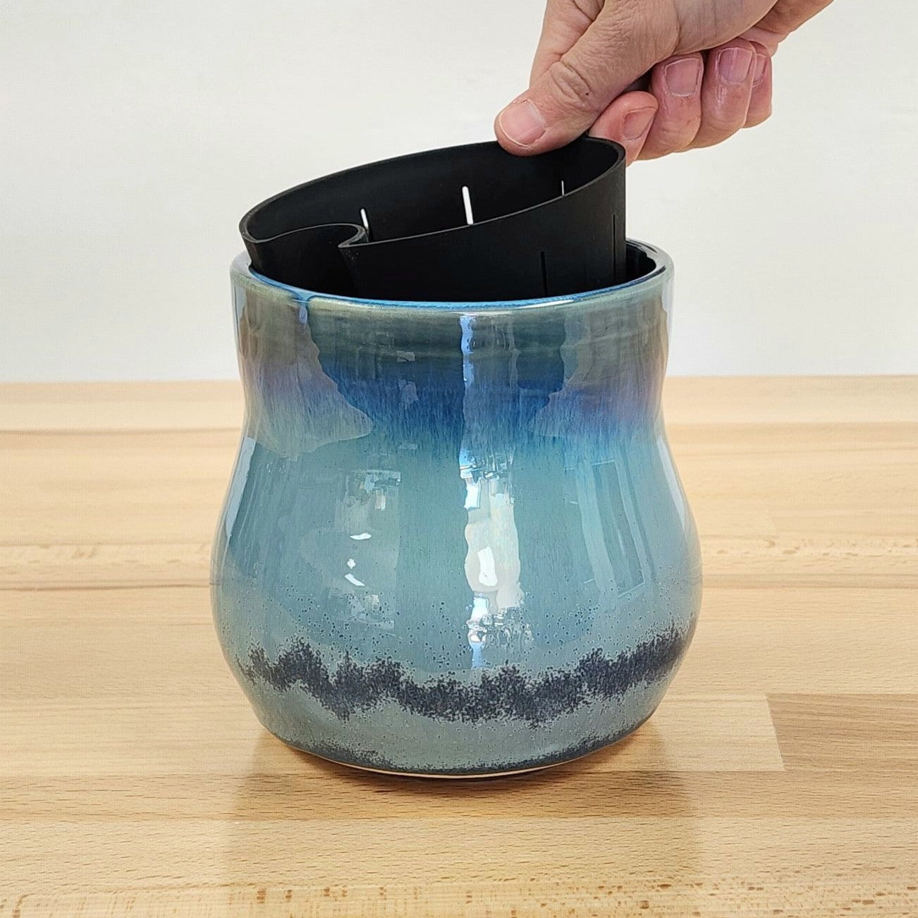 A hand is lifting the black, flexible removable liner out of the &