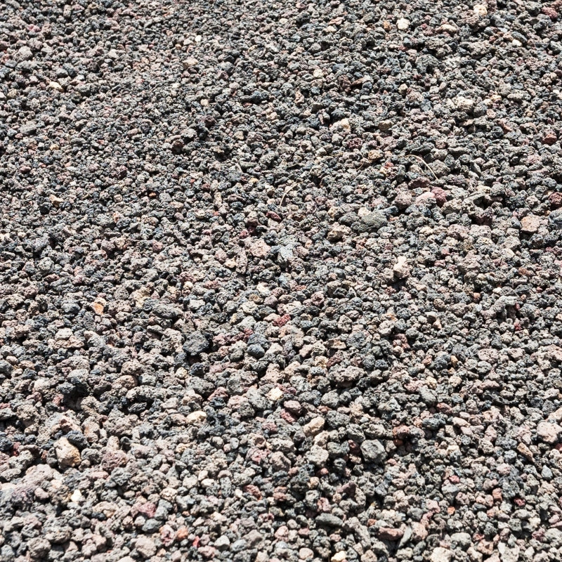 A close-up view of light, porous volcanic pumice, highlighting its rough texture and natural composition under sunlight.